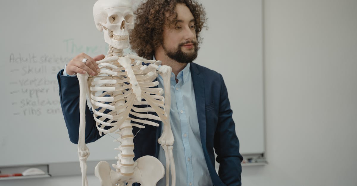 Educator demonstrating human skeleton model during a biology lesson in a school classroom.