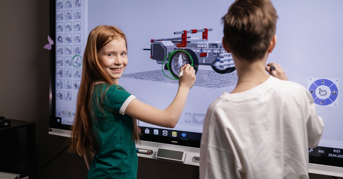Two children interacting with a digital screen in a classroom setting, learning through technology.
