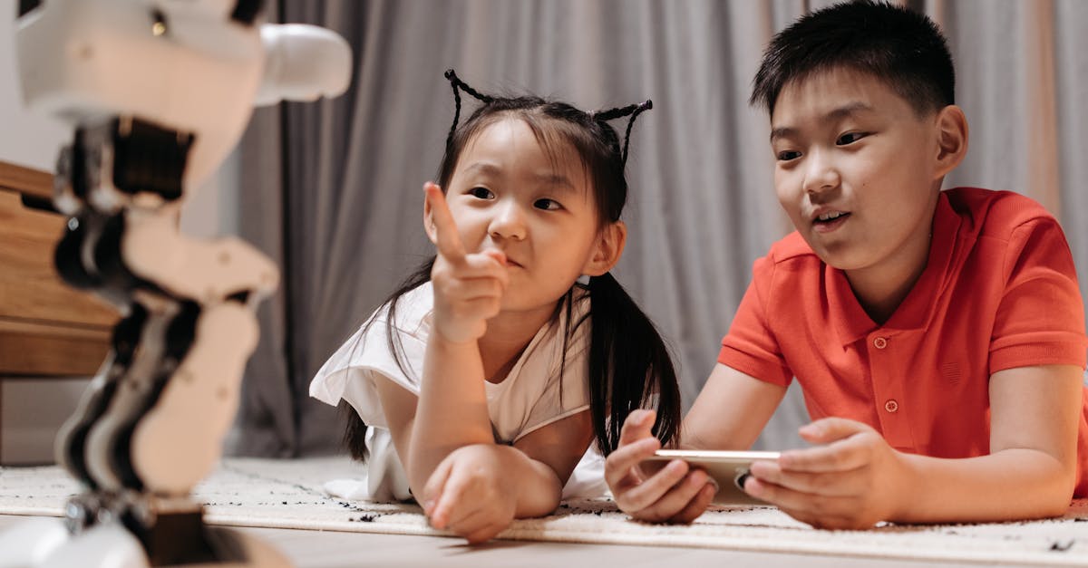Two children interact with a robotic toy while using a smartphone, showcasing modern technology indoors.