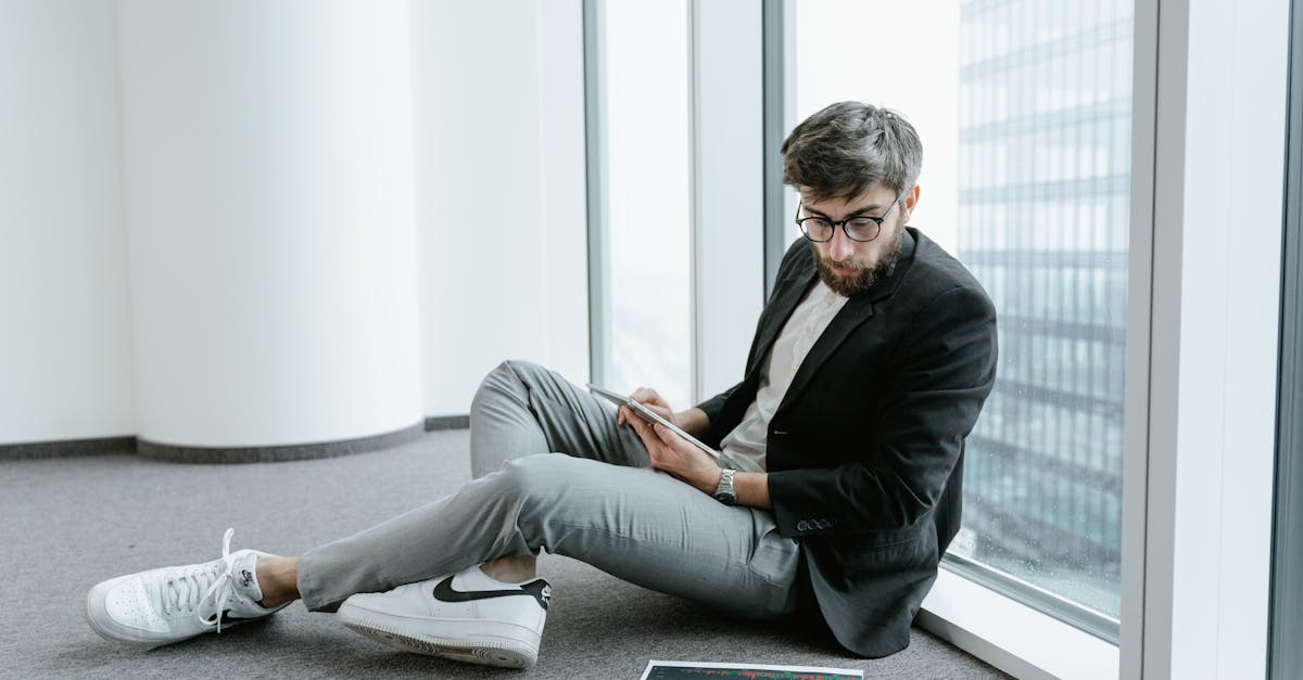A man in an office setting using a tablet to analyze stock market data with graphs.
