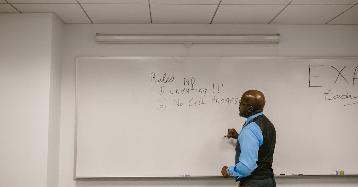 Instructor writing exam rules on a whiteboard in a college classroom.