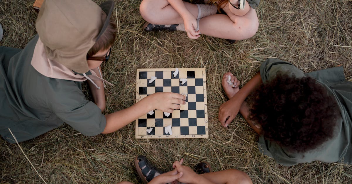 A group of kids playing chess on grass, enjoying a strategic game in summertime.