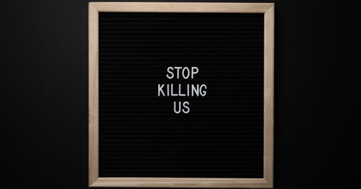 Top view of slogan Stop Killing Us on surface of square blackboard on black background