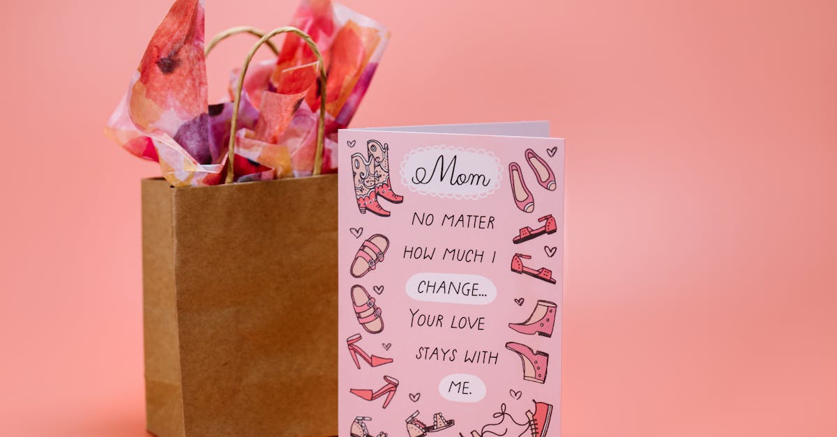 Mother's Day card with heartfelt message and gift bag on pink surface.