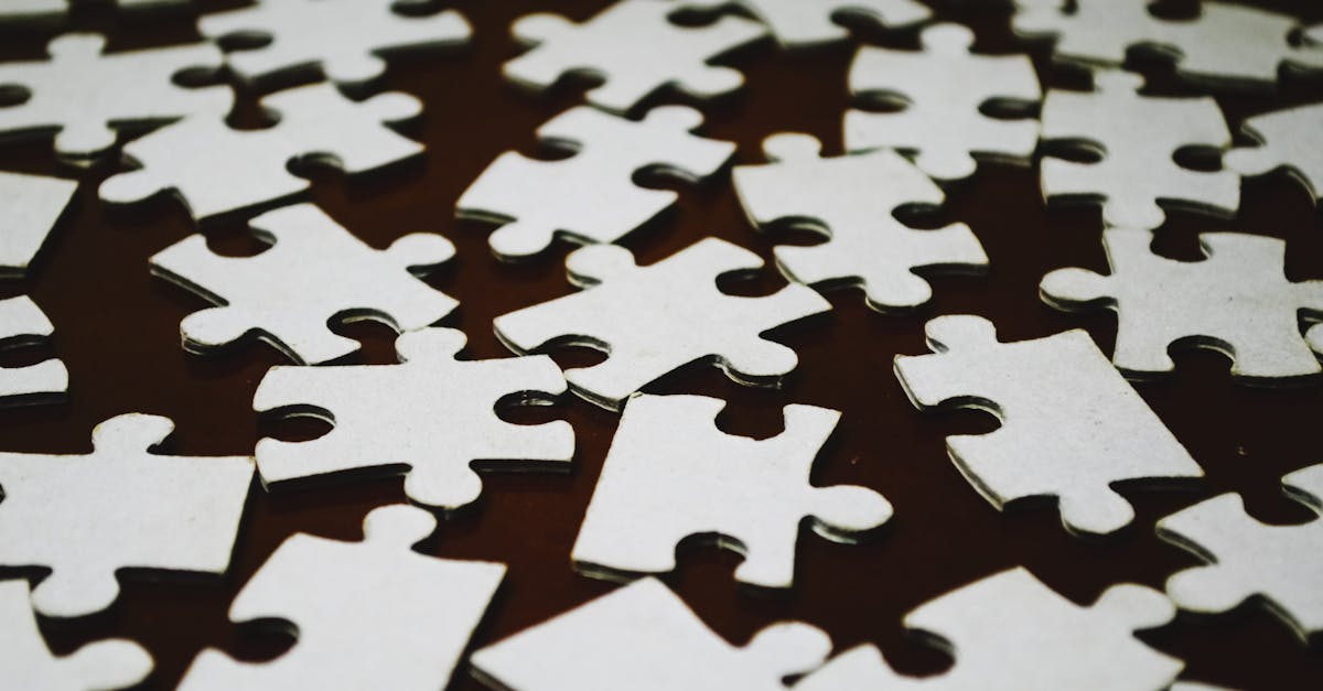 Detailed close-up view of scattered white jigsaw puzzle pieces on a dark surface.