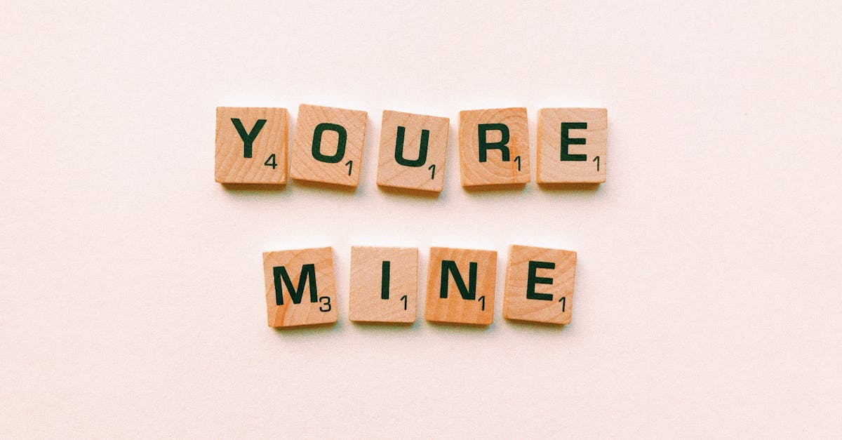Romantic message You're Mine created with wooden Scrabble tiles on a pink background.