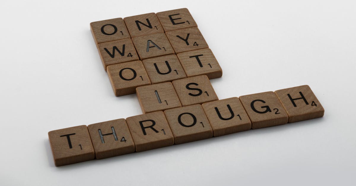 Close-up of Scrabble tiles spelling 'one way out is through' on a white surface.