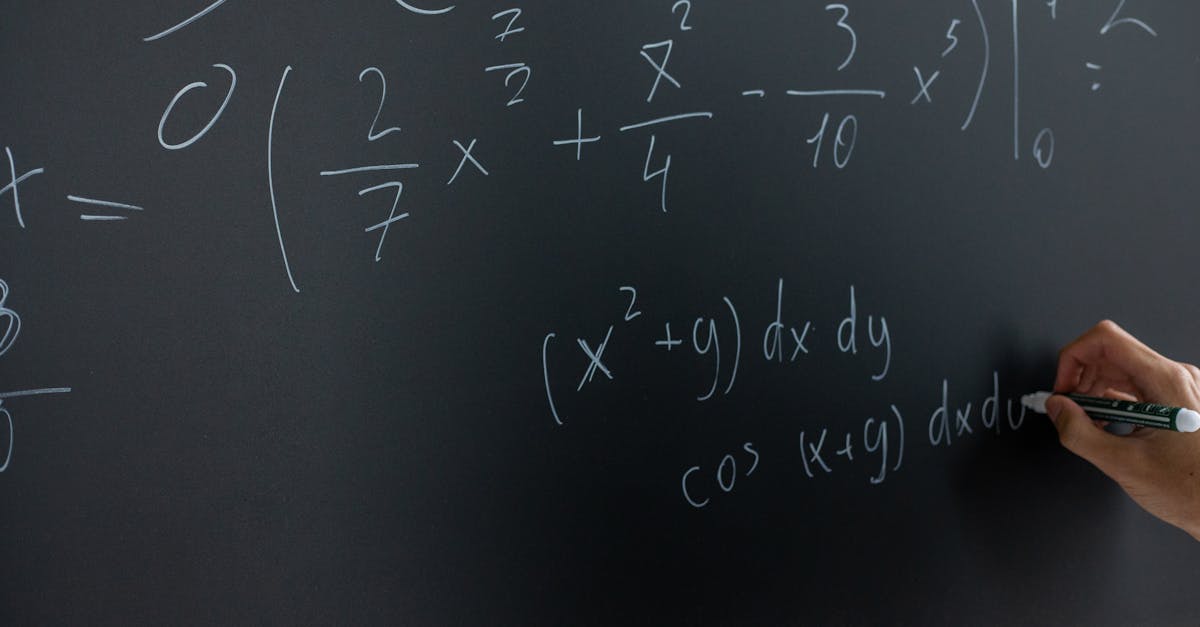 Hand writing mathematical equations on a chalkboard in a classroom setting.