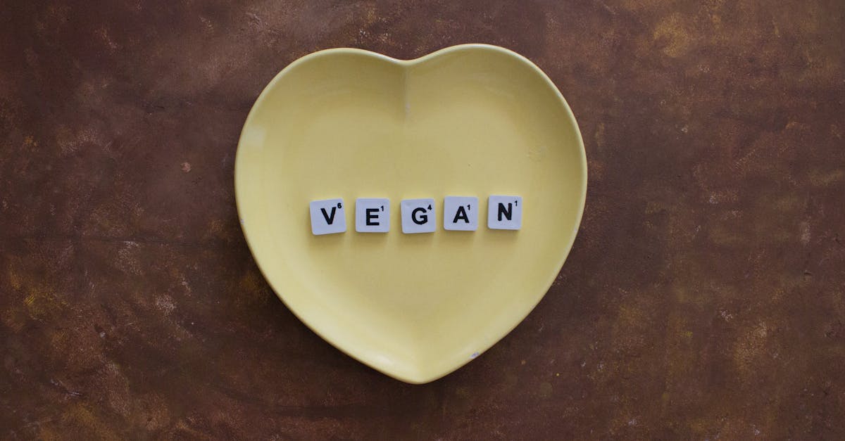 Yellow heart plate with letters spelling 'VEGAN' on a brown textured background.