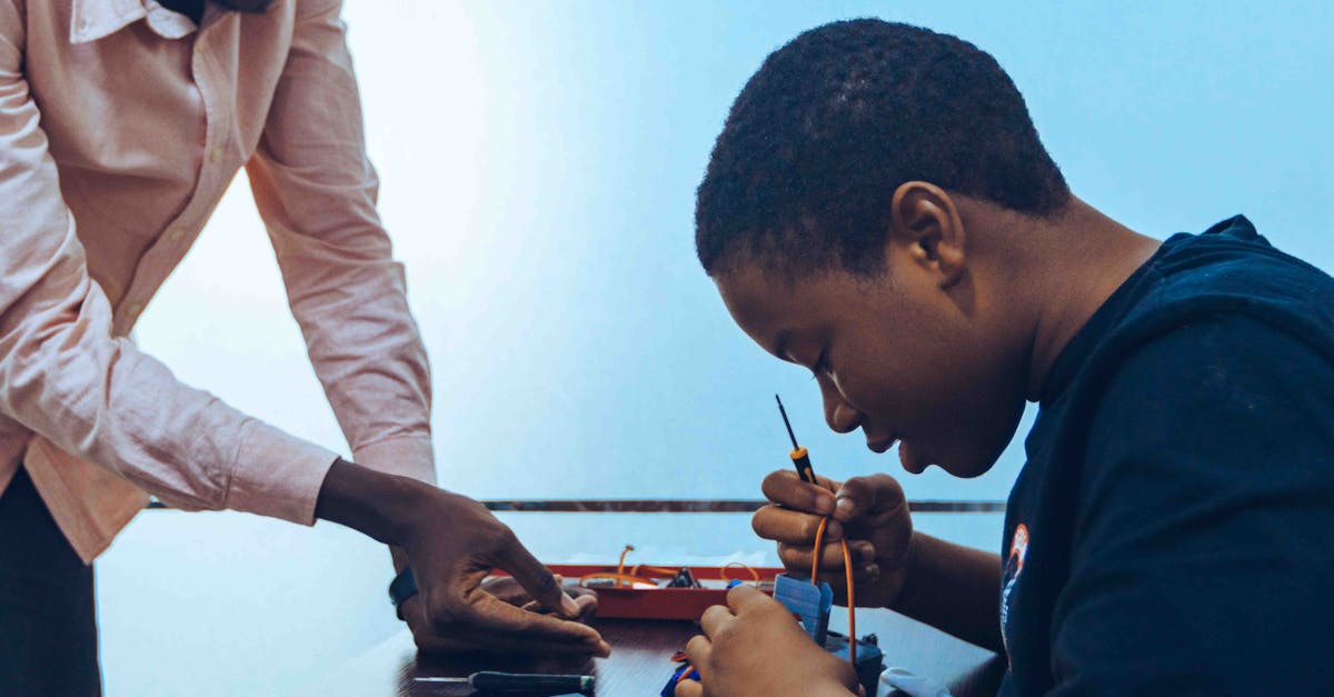 A student and a teacher engage in practical electronics learning in a classroom environment.