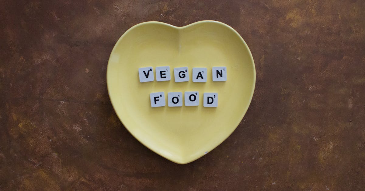 Yellow heart-shaped plate with scrabble tiles spelling 'vegan food' on a rustic background.
