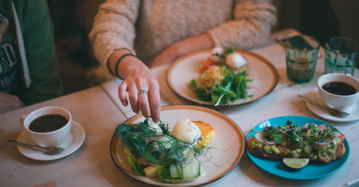 Crop anonymous female eating healthy meal served on plate with coffee on table in restaurant