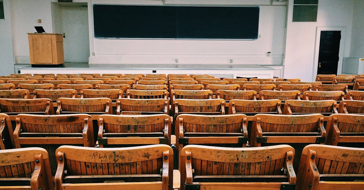 An empty lecture hall featuring wooden chairs and a large blackboard.