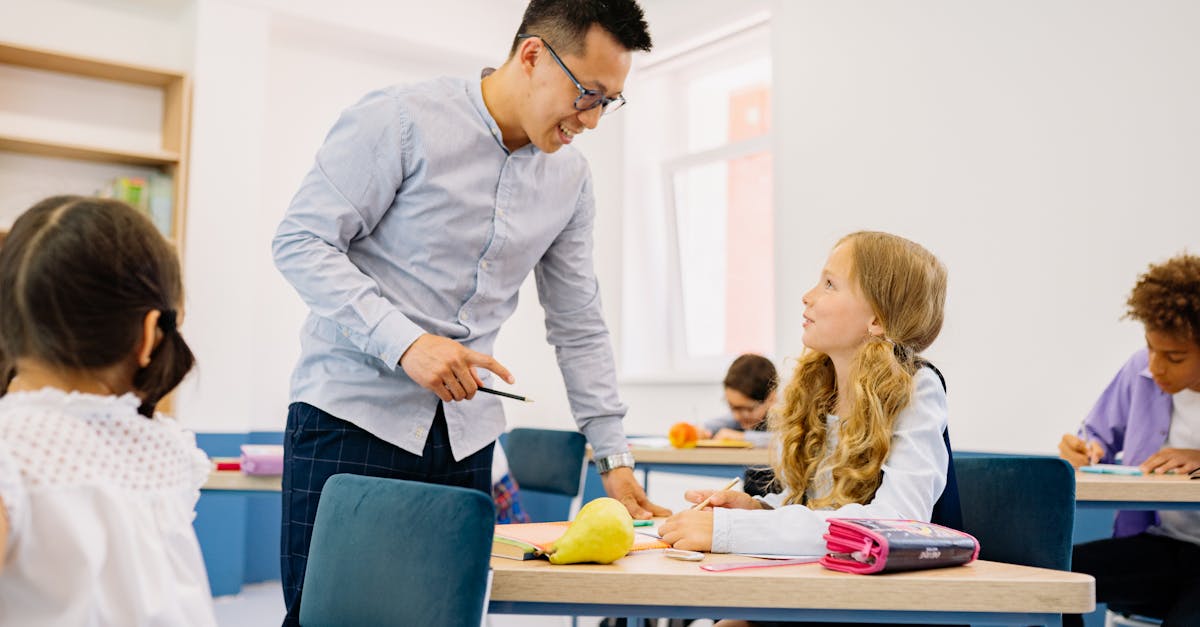 A male teacher interacting with diverse students in a bright classroom setting, promoting active learning.