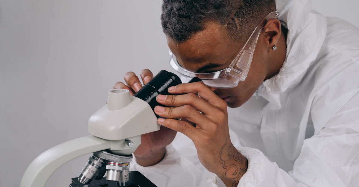 Scientist in PPE focuses on laboratory research using a microscope indoors.