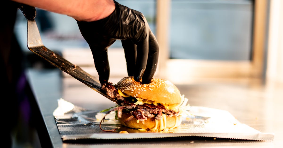 A chef skillfully prepares a gourmet burger with unique toppings in a professional kitchen setting.