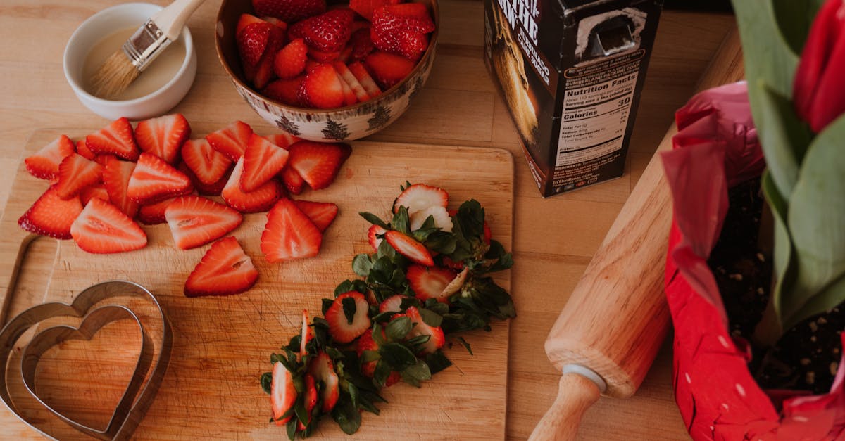 Sliced strawberries on a cutting board with a rolling pin and tulips for a fresh kitchen vibe.