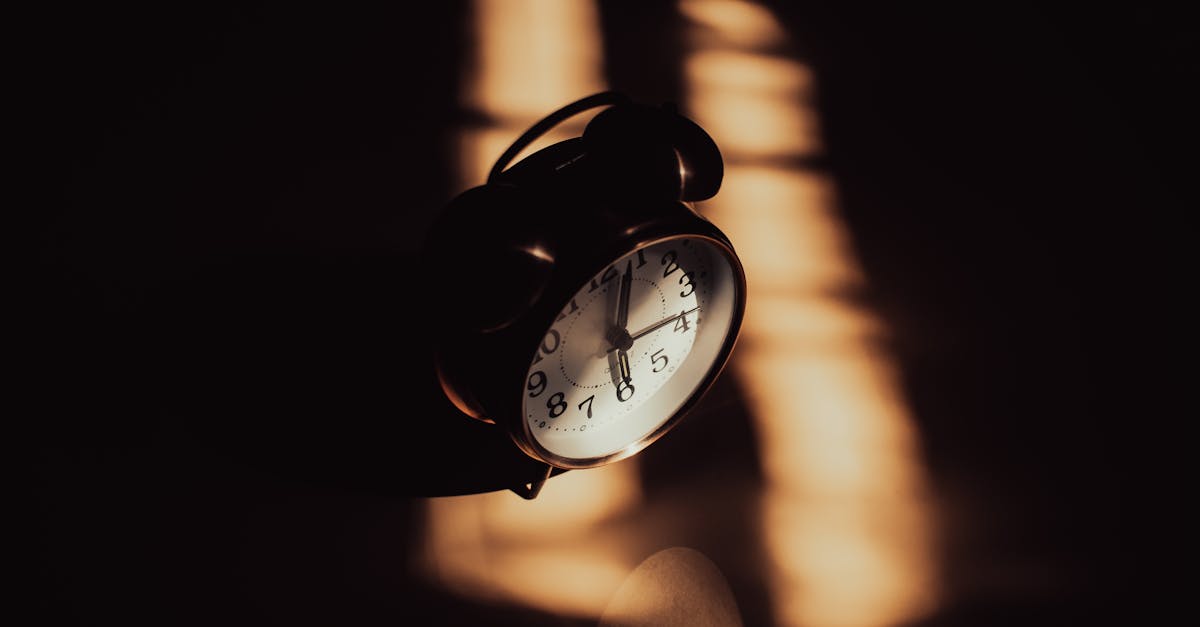 A retro analog alarm clock in moody shadows and warm lighting.