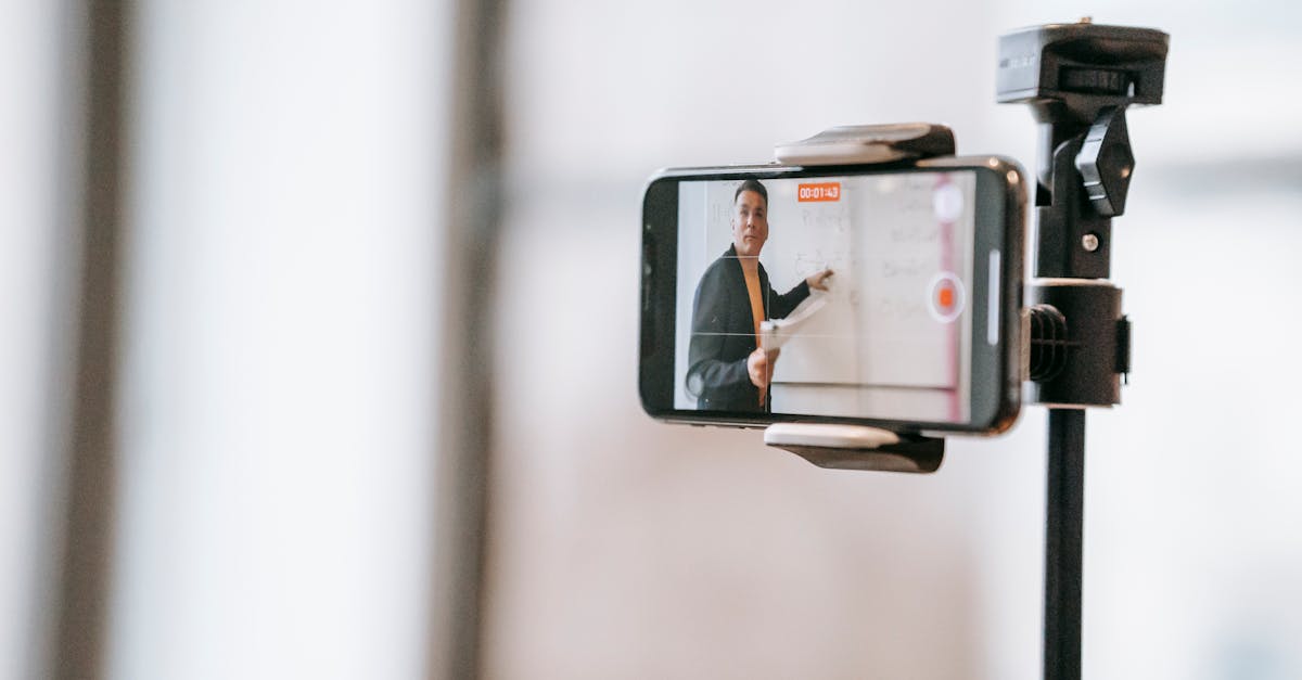 A lecturer conducting an online class using a smartphone mounted on a tripod.
