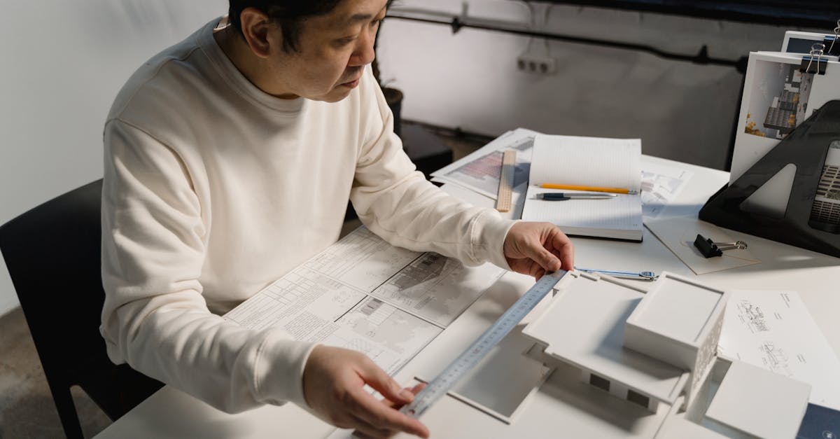 Architect examining a scale model with precision tools at an office desk.