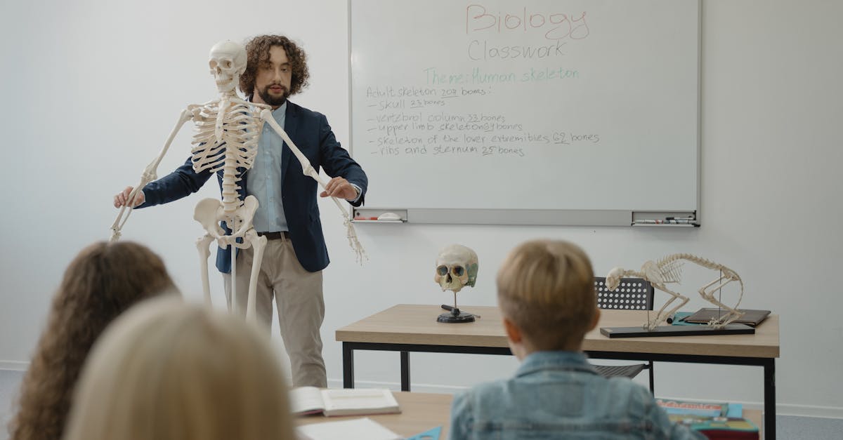 Teacher explaining human skeleton to students in a biology class with models.