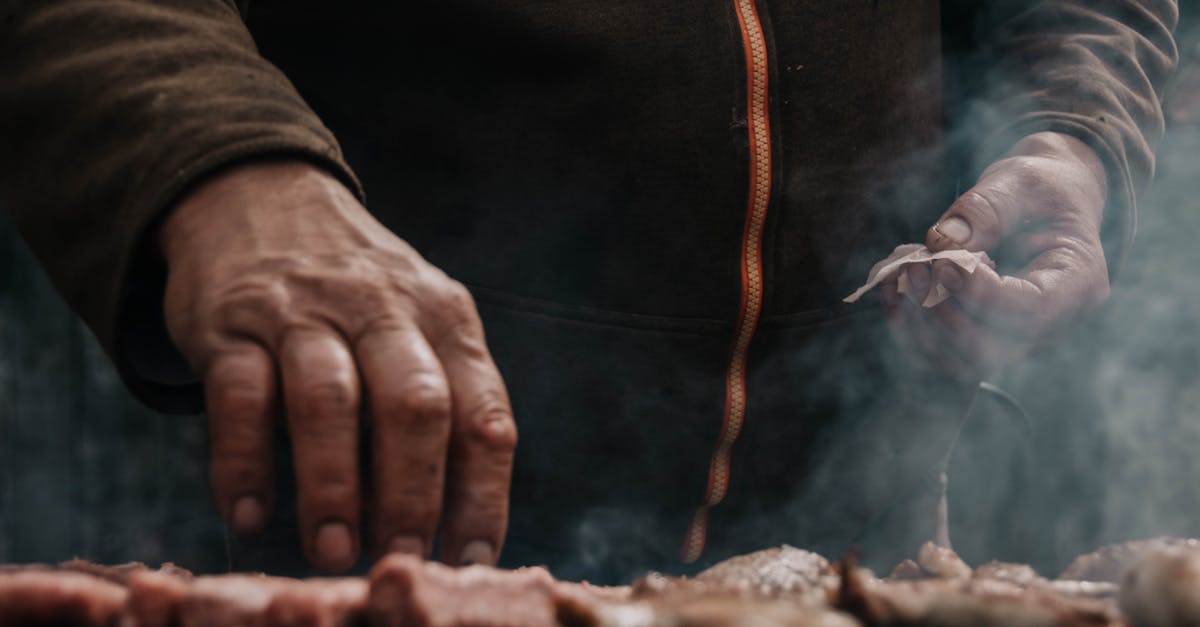 Man grilling meat outdoors with smoke rising, Belgrade, Serbia.