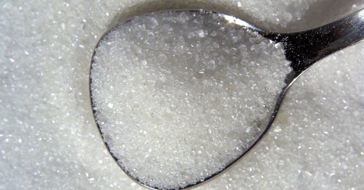 Detailed macro shot of white sugar crystals on a reflective spoon.