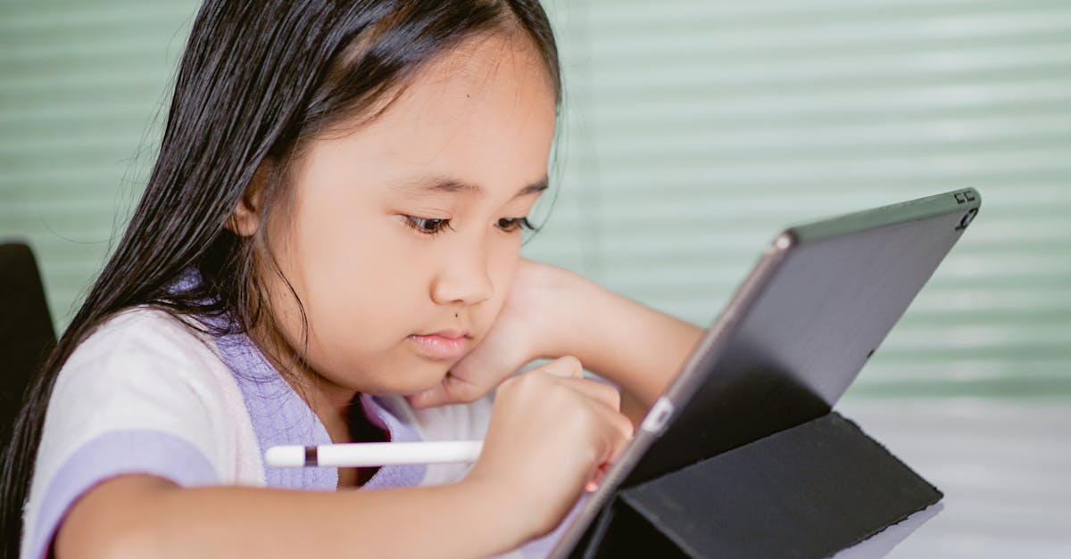 A young girl using a tablet for online learning, focused and engaged with her digital pen.