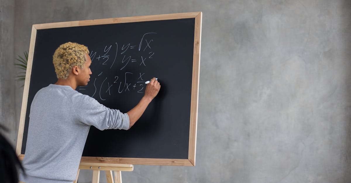 Back view of African American student with marker writing task on blackboard while studying in classroom