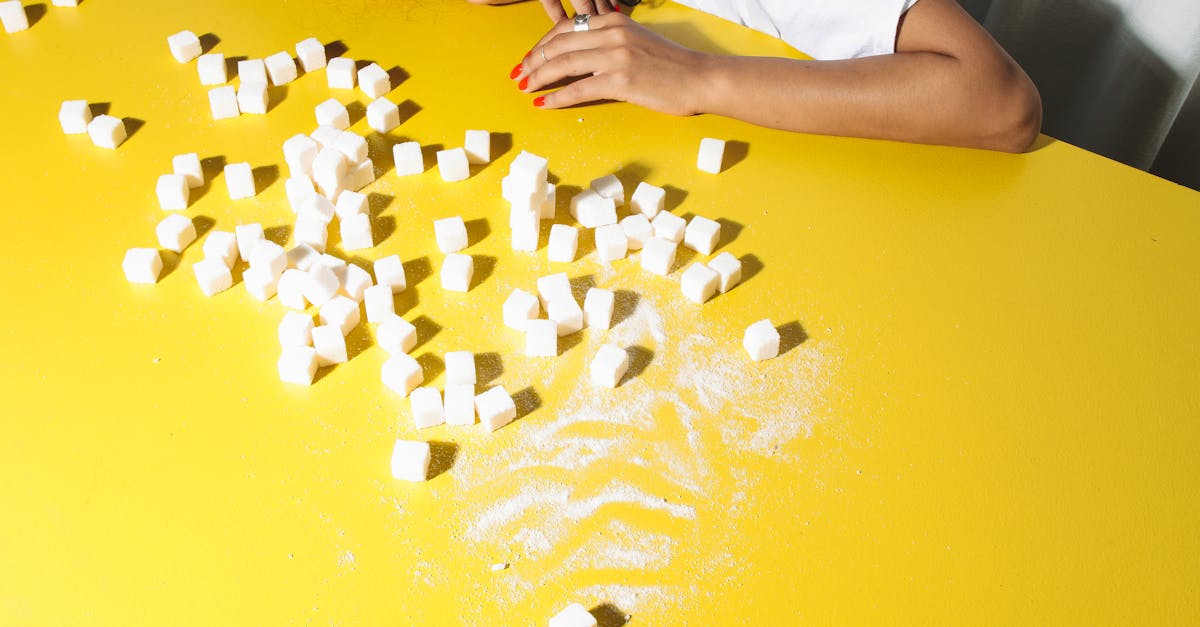 A woman contemplating sugar cubes on a bright yellow table, symbolizing health choices.