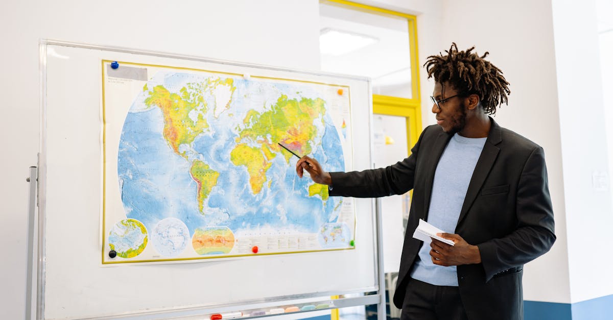 Teacher pointing at world map during classroom lesson, engaging students.