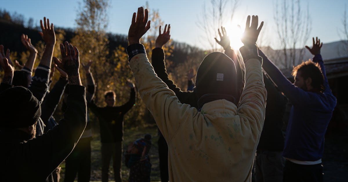 Group of people raising arms outdoors during sunrise for a refreshing exercise session.