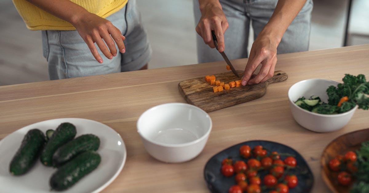 Two people preparing fresh vegetables on a wooden countertop.