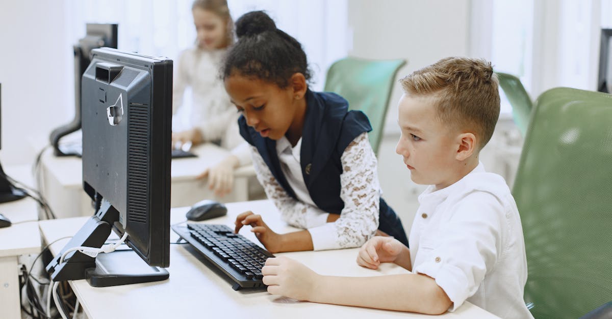 Diverse children working together on computers in a modern school setting.