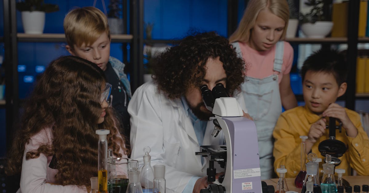 Students observe as a teacher conducts a chemistry experiment using a microscope in a laboratory.