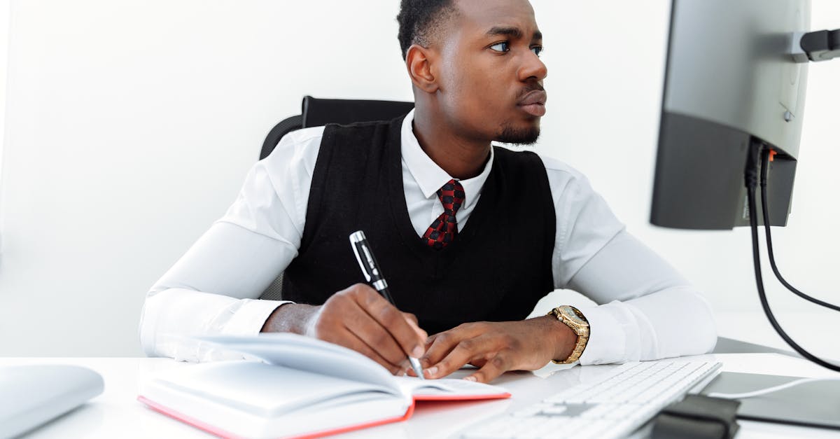 Professional businessman writing notes while working on a computer in a modern office.