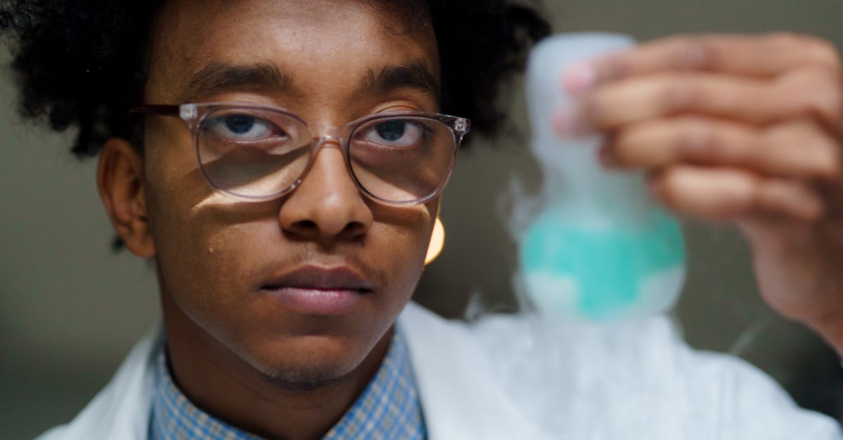 Focused young scientist examining a flask with blue liquid in a lab setting.