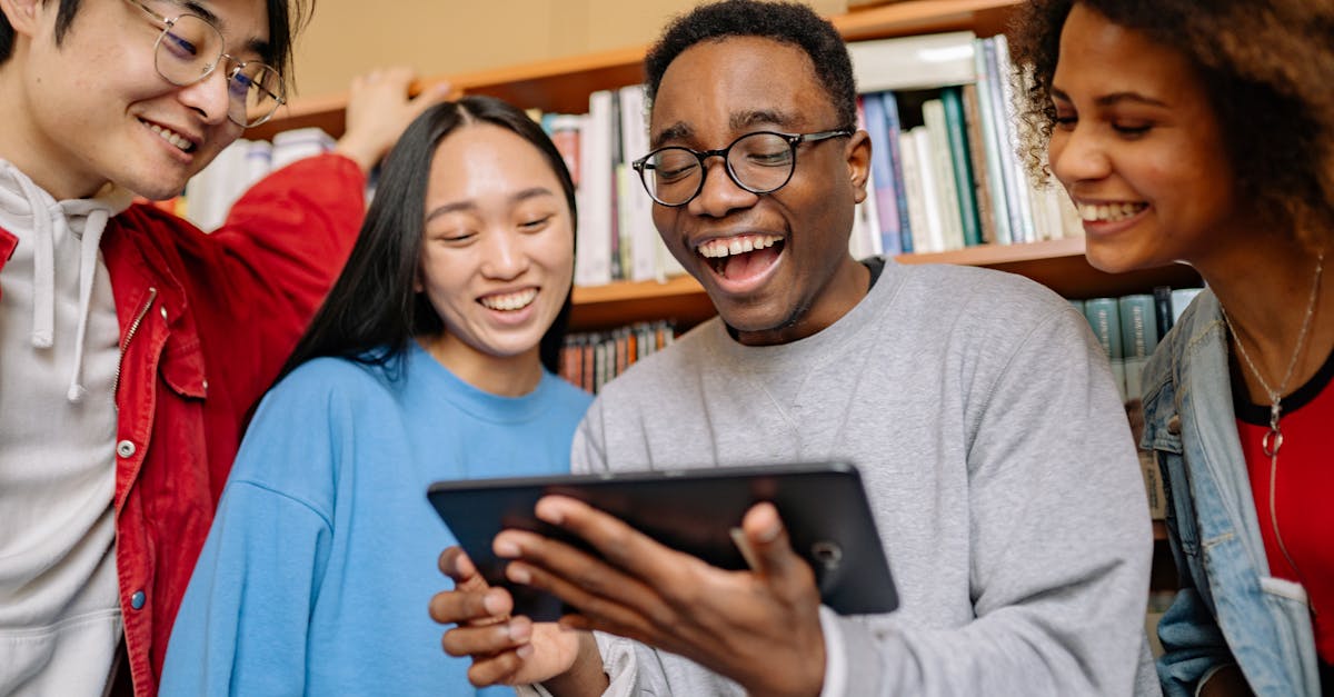 A group of diverse students enjoying studying together in a library, using a digital tablet.