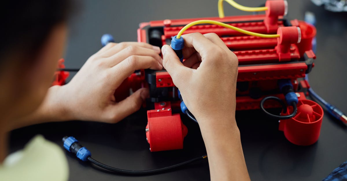 Close-up of hands assembling a robotic project with cables indoors, showcasing technology and electronics.