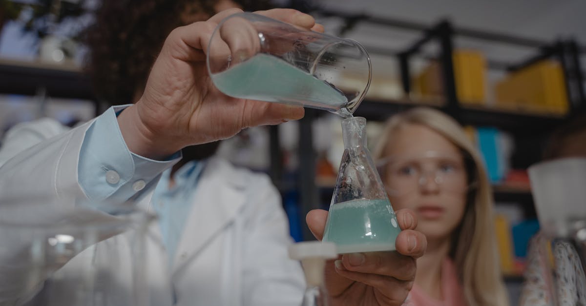 A student watches a teacher pour chemicals in a chemistry class experiment.