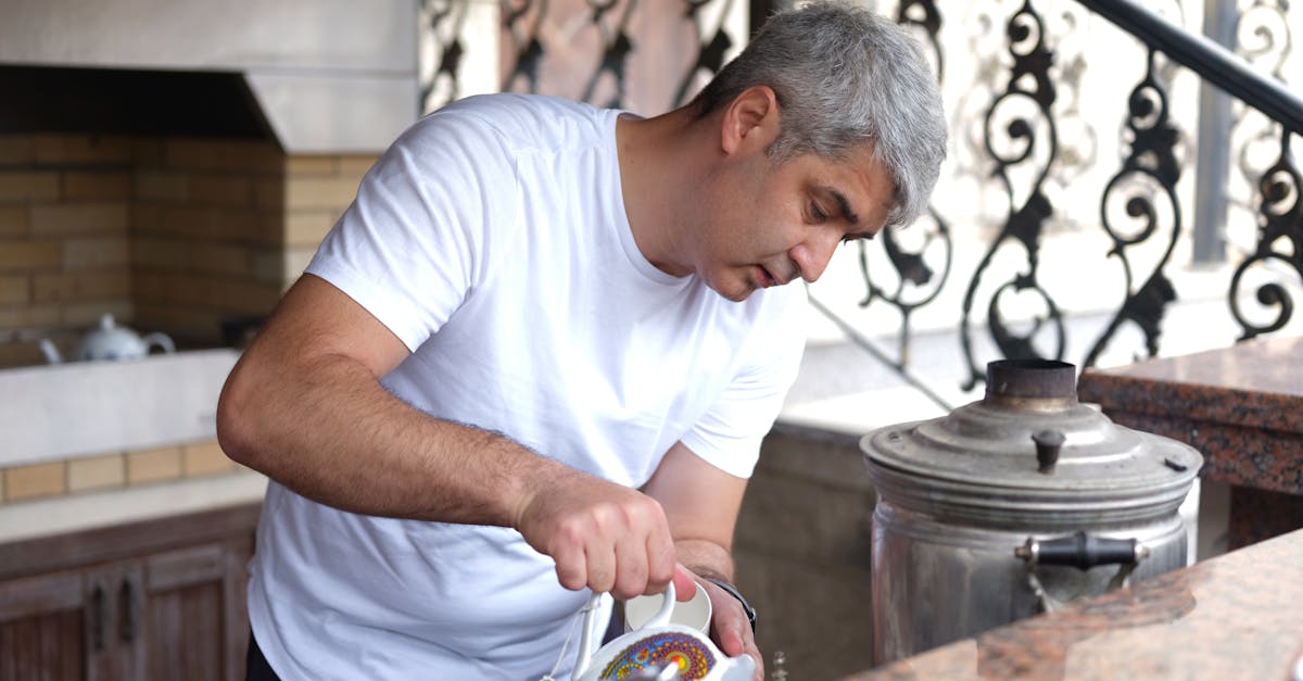 Adult man pouring tea from samovar in an outdoor kitchen setting, showcasing cultural traditions.