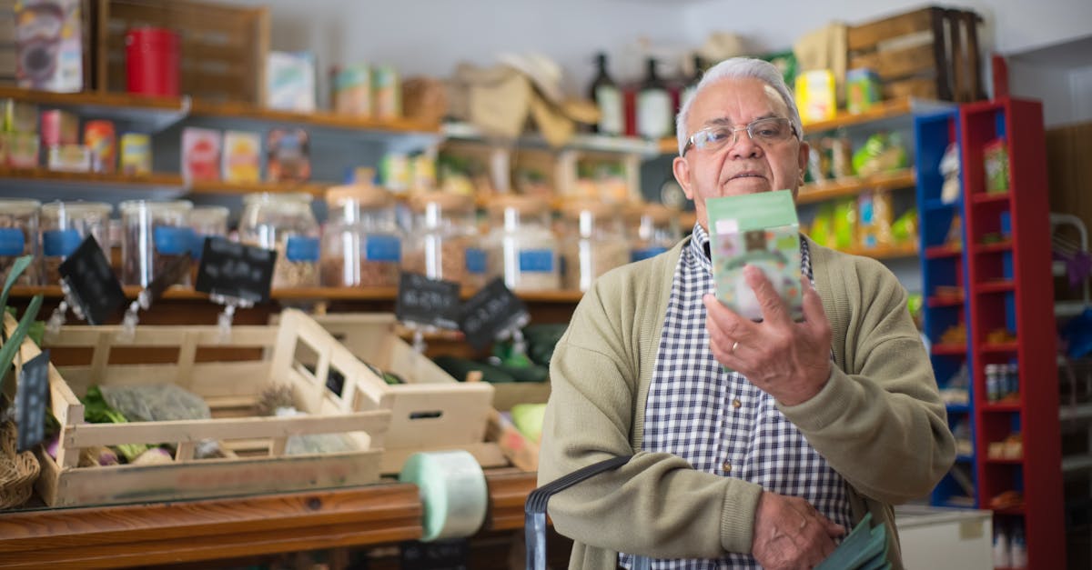 Elderly man examines product in grocery store aisle, representing daily shopping routine.