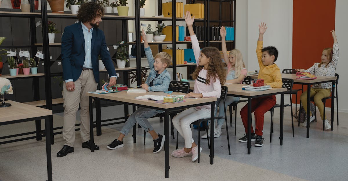 Children actively participating by raising hands during a class session, guided by their teacher.