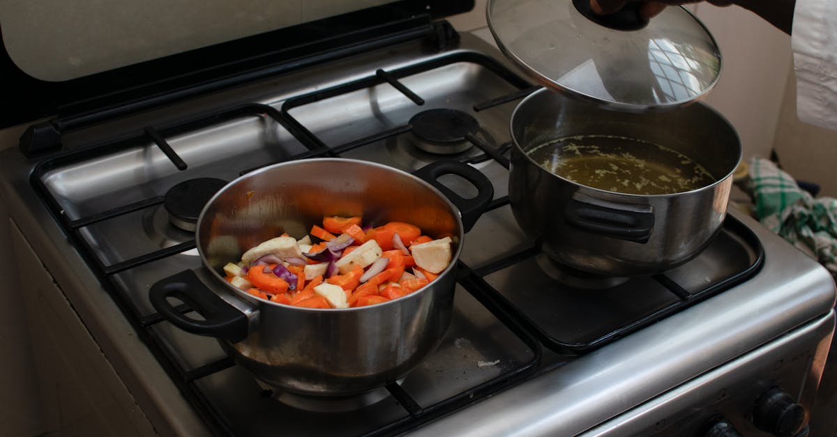 A kitchen scene featuring fresh vegetables being cooked in pots on a gas stove.