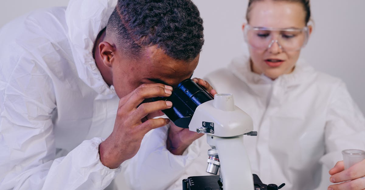 Two scientists in a laboratory examining samples through a microscope, focusing on scientific research.