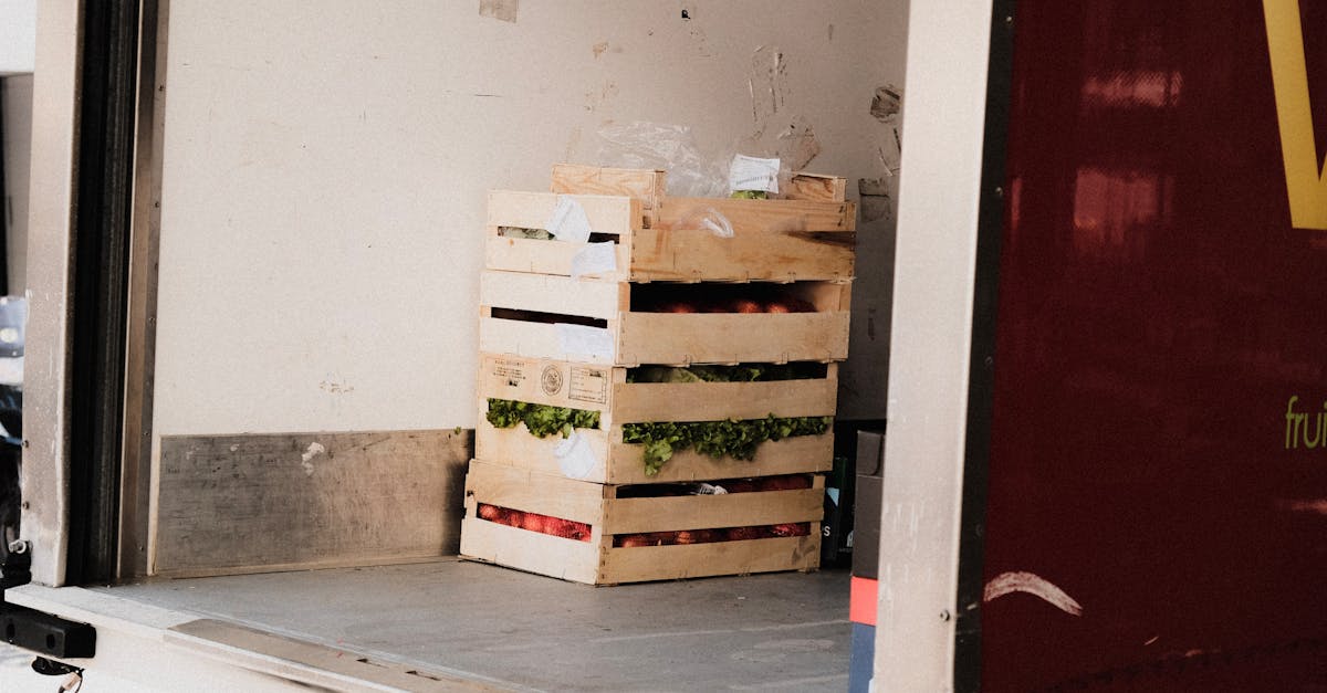 A wooden crate with fresh vegetables loaded inside a delivery truck, ready for transportation.