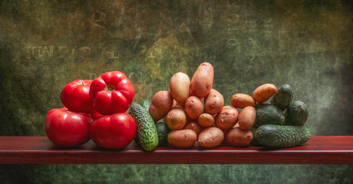 A rustic display of fresh tomatoes, potatoes, and cucumbers on a wooden shelf against a textured background.