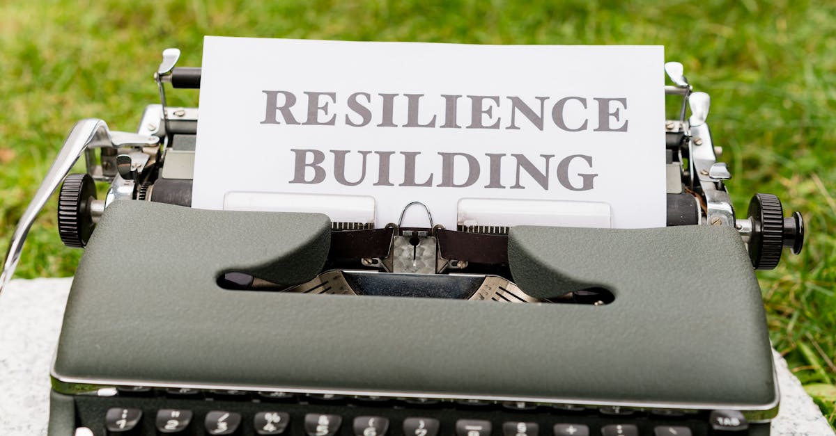 Vintage typewriter with 'Resilience Building' text on paper, set outdoors on grass.