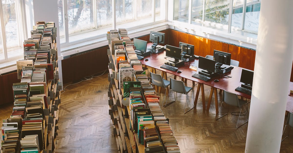 A university library viewed from above, featuring bookshelves and computer stations under natural daylight.