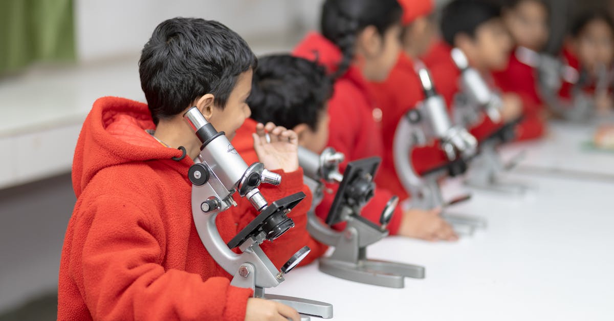Young students in red exploring science with microscopes in a classroom setting.